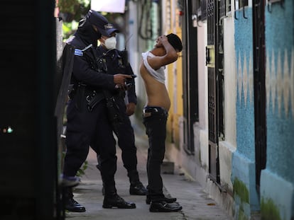 A police officer searches a man in Soyapango, El Salvador