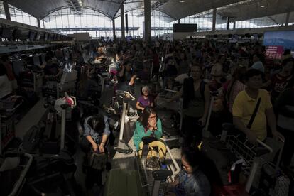 Un rayo de luz ilumina a los pasajeros que hacen cola para realizar el check-in en la zona de salidas del aerpouerto de Hong Kong, el 13 de agosto de 2019. Los manifestantes han bloqueado la zona de facturación este martes después de forzar el lunes a cerrar uno de los aeropuertos más concurridos del mundo.