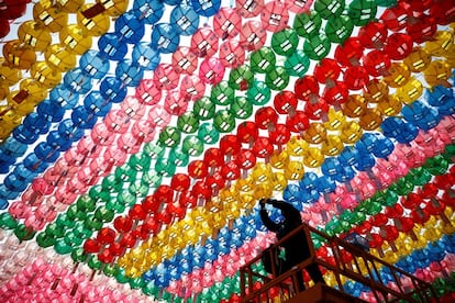 Un operario coloca peticiones de oración en las lámparas de papel durante los preparativos para el próximo cumpleaños de Buda, en el templo Jogye de Seúl (Corea del Sur).