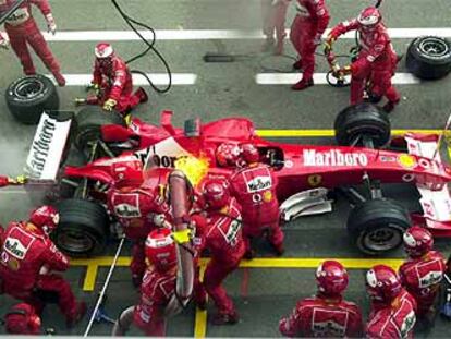Los mecánicos se apresuran a apagar un incendio en el Ferrari de Michael Schumacher durante un repostaje.