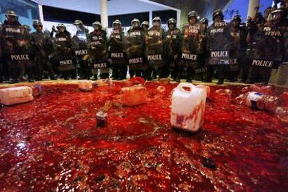 Un grupo de policías, junto a la sangre derramada por los manifestantes ante el palacio gubernamental en Bangkok.