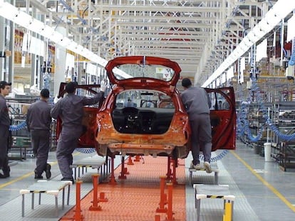 Un grupo de operarios trabaja en una planta de ensamblaje de automóviles.