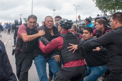 El ministro de Seguridad bonaerense, Sergio Berni, sale escoltado por varios agentes de la manifestación de conductores de autobús donde fue agredido este lunes.
