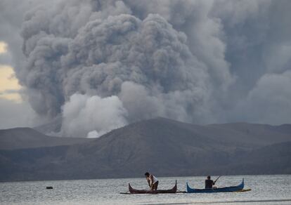 Dos campesinos pescan, en la provincia de Batangas (Filipinas), al fondo el volcán Taal en erupción.