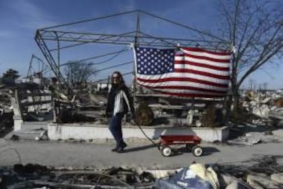 Una mujer pasa delante de una casa destruida por el paso del Huracán Sandy en Breezy Point, Nueva York, EE.UU..