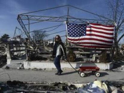 Una mujer pasa delante de una casa destruida por el paso del Huracán Sandy en Breezy Point, Nueva York, EE.UU..