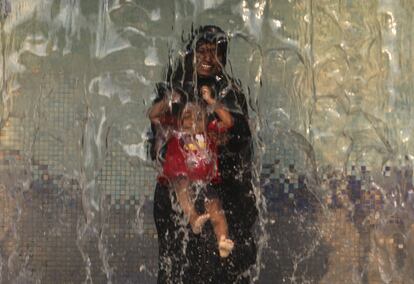 Una mujer india juega con su hijo en un parque acuático en Hyderabad en la víspera del Día Mundial del Agua.