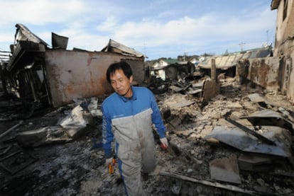 Un hombre camina entre los escombros de las casas arrasadas por el bombardeo en Yeonpyeong.