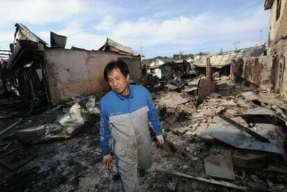 Un hombre camina entre los escombros de las casas arrasadas por el bombardeo en Yeonpyeong.