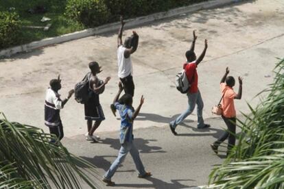 Un grupo de civiles anda con las manos arriba en las cercanías del palacio de Abiyán, donde las tropas leales a Gbagbo custodian las calles.