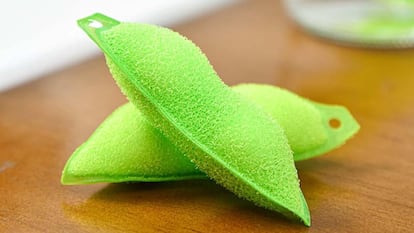 Dos esponjas en forma de edamame sobre una mesa de madera que sirven para limpiar el interior de las botellas.