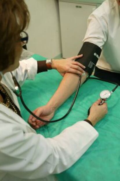 Una doctora tomando la tensi&oacute;n a un paciente.