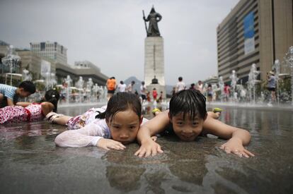 Los niños se refrescan en un día caluroso de verano frente a la estatua del General Lee Pronto-shin en Gwanghwamun, Seúl, Corea del Sur.