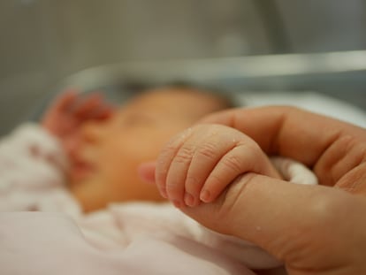 Una madre sostiene la mano de su bebé recién nacido en el hospital.