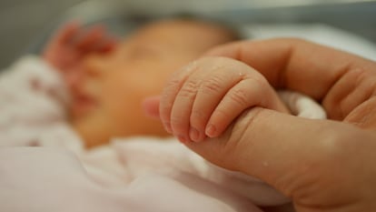 Una madre sostiene la mano de su bebé recién nacido en el hospital.