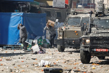 Varias personas corren a cubierto durante los disturbios de este miércoles entre palestinos y militares israelíes, en las calles de Nablus.