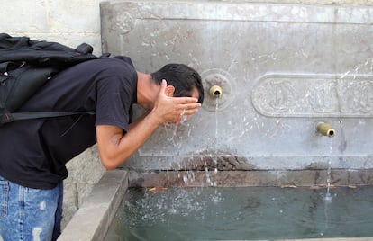 Un joven se refresca durante una ola de calor del verano, en Granada, Andalucía.