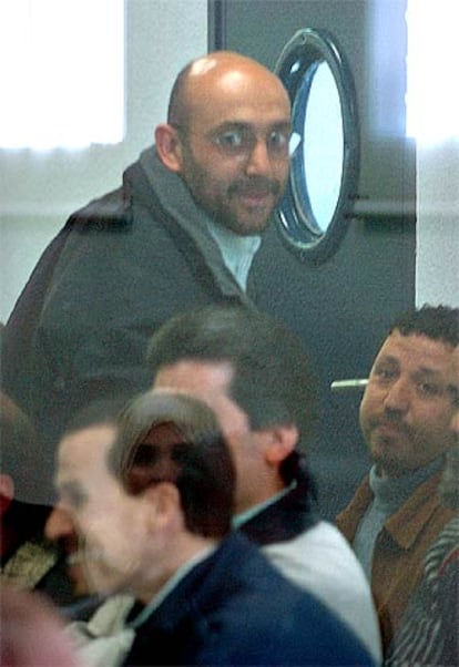 Imad Eddin Barakat Yarkas, alias <I>Abu Dahdah</i>, de pie, junto a otros acusados en el recinto acristalado desde el que siguen el juicio contra ellos.