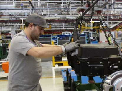 Dos operarios colocan las bater&iacute;as de la furgoneta el&eacute;ctrica Citro&euml;n Berlingo en la cadena de montaje de la planta de PSA. 