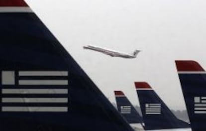 Un avi&oacute;n de American Airlines despega entre aviones de US Airways estacionados en el aeropuerto Ronald Reagan de Washington.