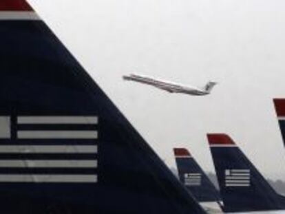 Un avi&oacute;n de American Airlines despega entre aviones de US Airways estacionados en el aeropuerto Ronald Reagan de Washington.