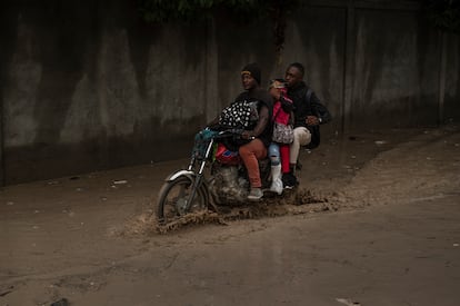 People on a motorcycle drive down a flood street in Port-au-Prince.