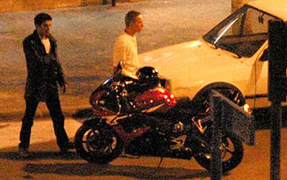 El atracador (izquierda) con uno de sus rehenes se dirige a la motocicleta en la que huyó.