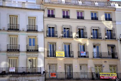 Fachada de un edificio de Madrid con diferentes carteles de venta y alquiler de pisos. 