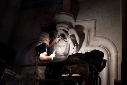 El escultor Jaume Casas da los últimos toques al dintel afectado por el incendio.