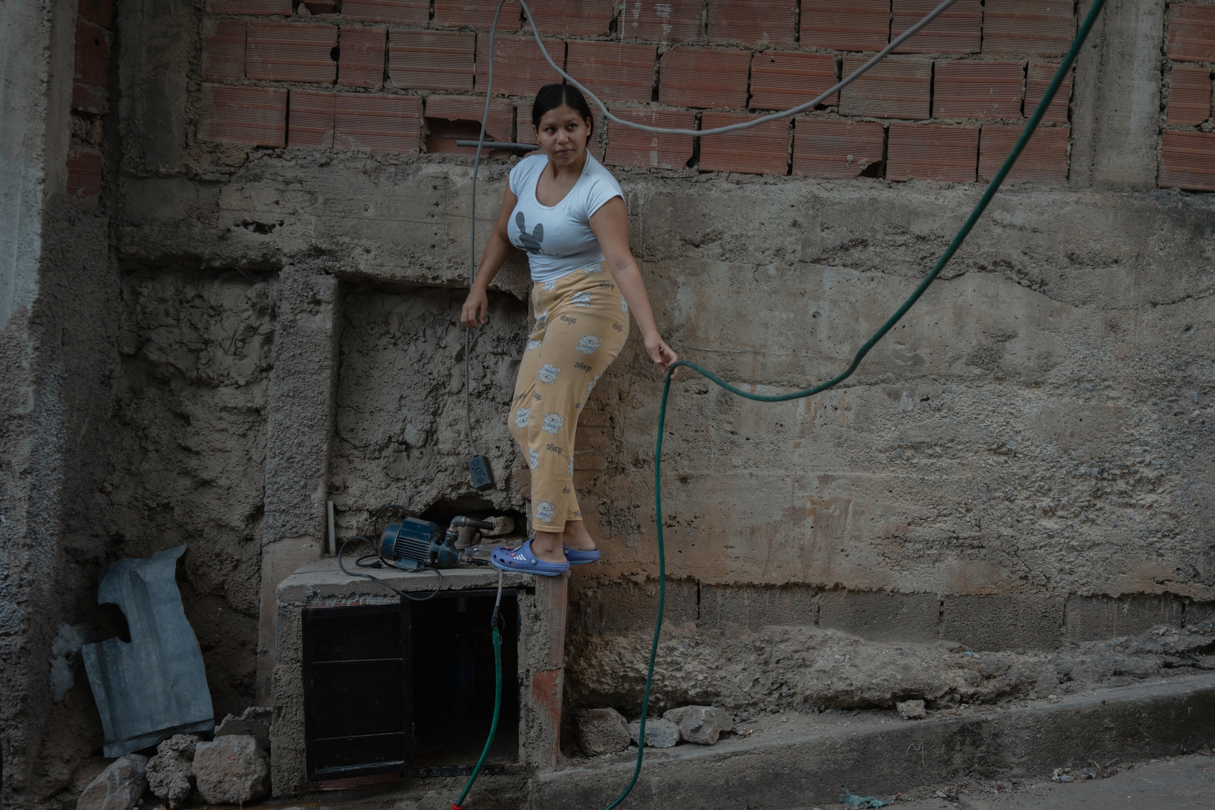 Una mujer recoge la bomba para recolectar agua en Petare, Caracas.