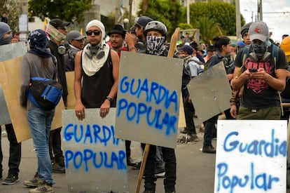 Manifestantes sujetan pancartas en las que se puede leer "Guardia popular", durante una protesta en Quito (Ecuador). 