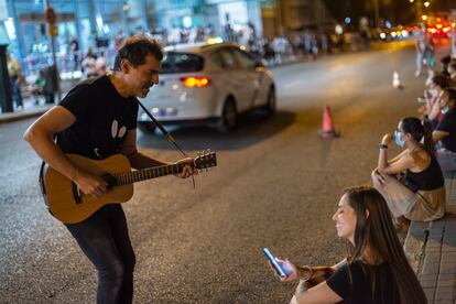 Un hombre toca la guitarra enfrente del Wizink Center mientras las personas esperan a que salgan sus amigos y familiares. 