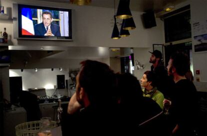 Un grupo de personas ve la entrevista del presidente francés, Nicolas Sarkozy, en la noche del jueves.