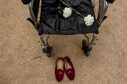 Una silla de ruedas vacía, con una flor blanca encima y unas pantuflas en el suelo, en recuerdo de las víctimas en las residencias de Madrid durante la pandemia, este miércoles.