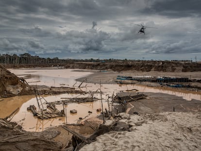 A police helicopter flies over an illegal mining area in the Madre de Dios region of Peru