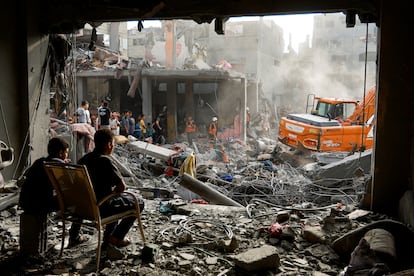 Dos personas observan los trabajos de desescombro de una zona afectada por los ataques israelíes, este miércoles en Jan Yunis. 