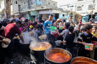 Unos voluntarios palestinos distribuyen comida caliente entre decenas de desplazados al sur de la franja de Gaza, este jueves cerca del paso fronterizo de Rafah.