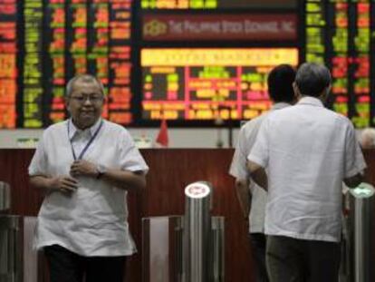 Corredores de bolsa filipinos atraviesan la entrada de la sede de la Bolsa de Filipinas (PSE) en la ciudad de Makati, al sur de Manila. EFE/Archivo