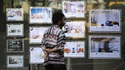 Un joven mira anuncios de alquiler de una inmobiliaria en Barcelona.