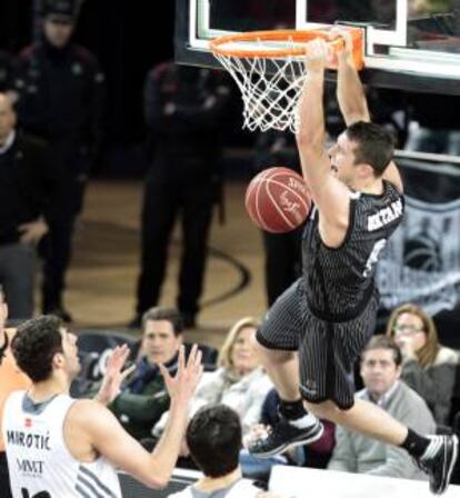 El escolta letón del Bilbao Basket, Dairis Bertrans (d), se cuelga del aro ante el jugador montenegrino del Real Madrid, Nikola Mirotic (i), durante el partido de la jornada 24 de la Liga ACB que enfrentó ayer a los dos equipos en el Bilbao Arena.