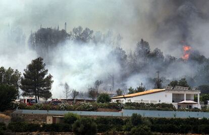 Las llamas del incendio de Cortes en una zona de chalés de Montroi (Valencia), el sábado.