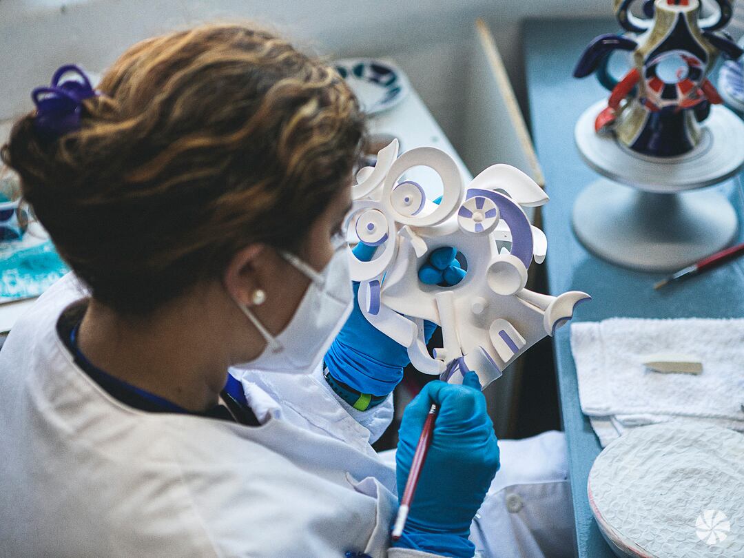 Una trabajadora pinta a mano la figura de porcelana de un búho.