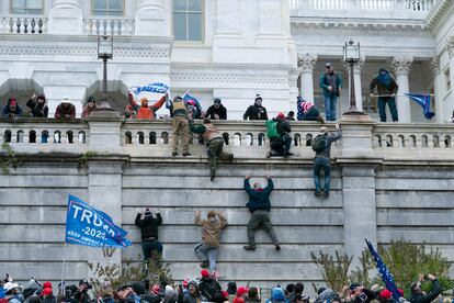 Seguidores del presidente Trump trepan un muro para intentar entrar en el Congreso de Estados Unidos, en Washington, este miércoles.