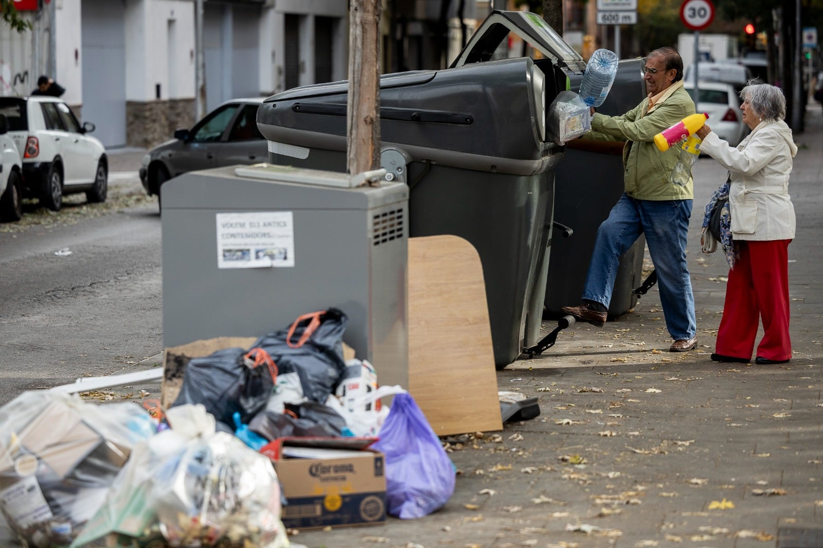 Dos vecinos de Girona se disponen a tirar la basura en los contendores.