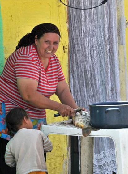 Una mujer prepara el pescado a la puerta de su casa.