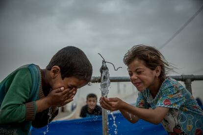 En los nueve países que se analizan en el informe 'El agua bajo el fuego 3: Ataques contra los servicios de agua y saneamiento en conflictos armados y los impactos en los niños' se estima que casi 48 millones de personas necesitan servicios de agua potable y saneamiento. En la imagen, Zahraa y Mahmood, dos niños de Mosul, ahora desplazados en el campamento de Khazer, se refrescan en uno de los grifos de agua instalados por la agencia humanitaria.