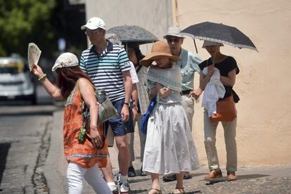 Un grupo de turistas se tapa con sombrillas o con pañuelos para seguir su visita por Córdoba.