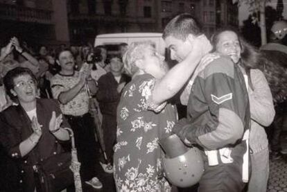 Una mujer abraza a uno de los <i>ertzaina</i>s que se quitaron la capucha en la sede de HB tras el asesinato de Miguel Ángel Blanco.