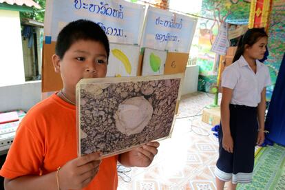 Uno de los niños que participan en el juego que UXO Lao lleva a cabo en Xieng Khuang para informar de los peligros que se esconden en su territorio muestra la fotografía de una pequeña bombita, el explosivo que más víctimas causa entre los más pequeños.