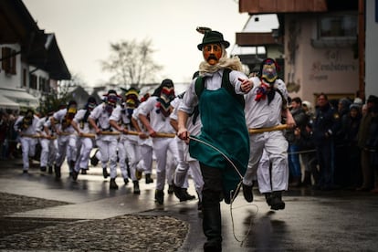 Varios participantes disfrazados con trajes tradicionales actúan durante el desfile de carnaval anual en Mittenwald (Alemania).